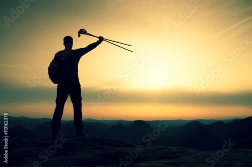 Silhouette with poles in hand above head. Sunny daybreak i
