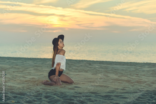 Portrait of beautiful happy woman in hat and shorts enjoying sunset beach background