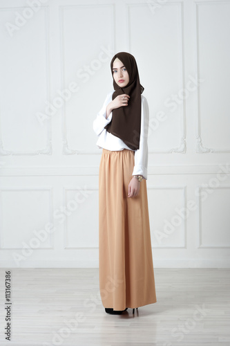 young woman of Middle Eastern appearance in the modern Muslim clothes and black scarf, a light classical background