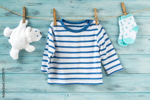 Baby boy striped shirt, socks with stars and white toy bear on a clothesline
