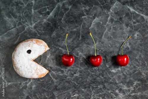 Powdered donut eating fresh cherries photo