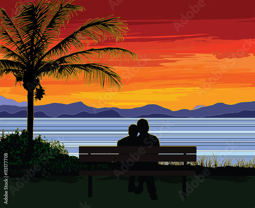 Silhouette of a romantic senior couple sitting on a bench by a palm tree, looking at the ocean and a beautiful colorful sunset.