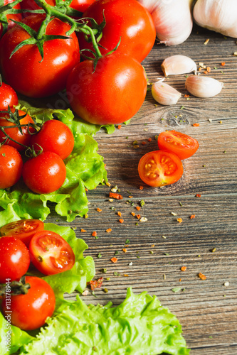 Fresh tomatoes with salad leaves on the table. Background.