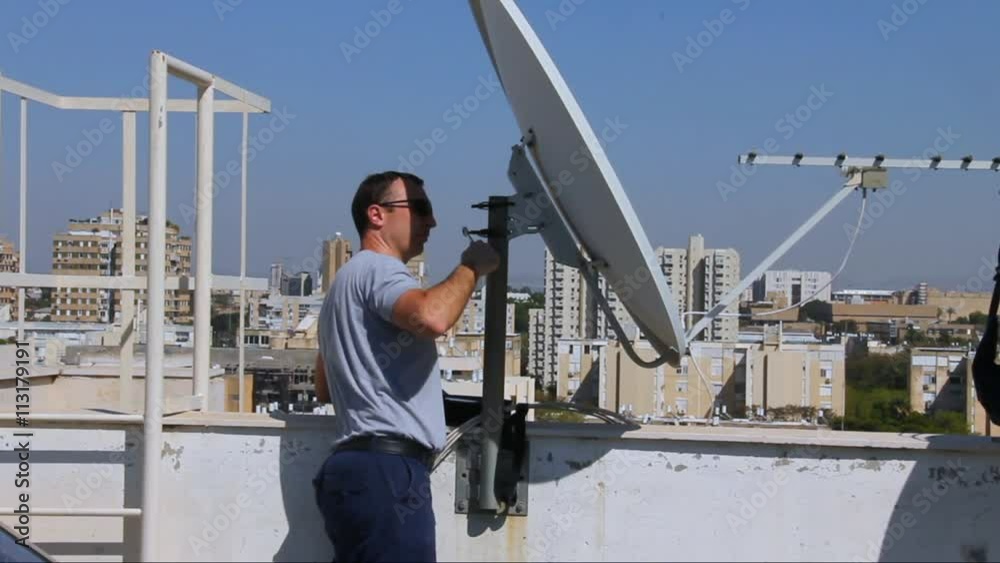 Technician adjusting of a satellite television plate with satellite channels finder, Technician adjusting of a satellite television plate with satellite channels finder,