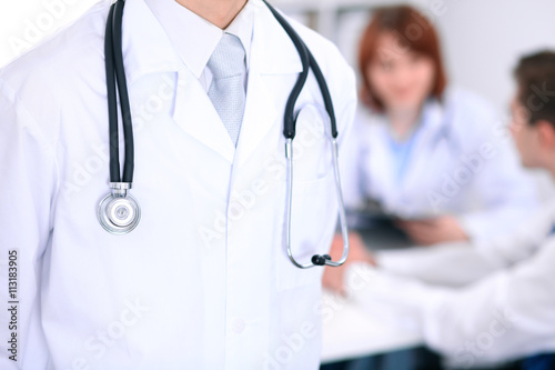 Close-up of a male doctor in a background of doctor and patient