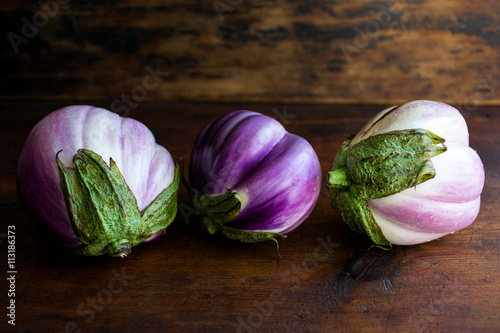 Three segmented purple eggplants on wood