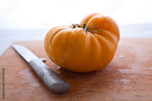 Yellow tomato and knife on cutting board