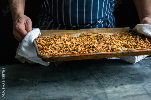 Person holding tray of baked granola photo