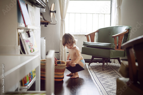 Shirtless girl (2-3) crouching and holding digital tablet photo