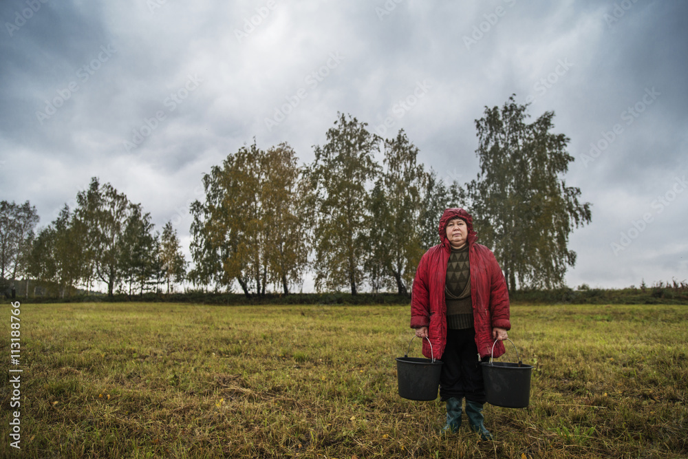Mature man with buckets standing in field Mature man with buckets standing in field