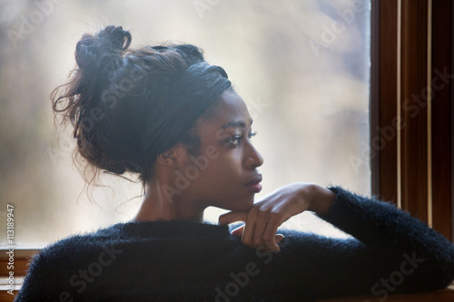Portrait of young woman standing by window photo