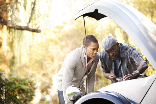 Man with his grandfather repairing a car engine