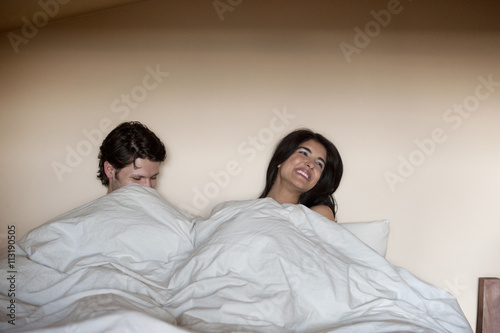 Young couple under cover in bed