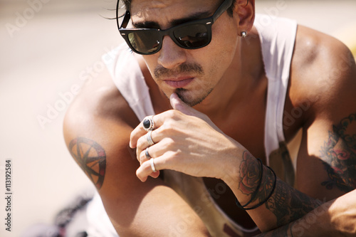 Young man with tattoos lying on beach