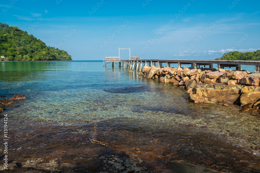 Clear sea water and wooden bridge with rocks