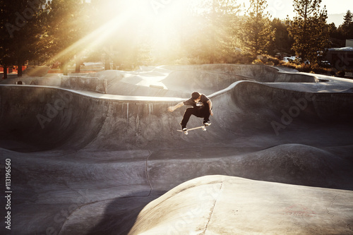 Skateboarder jumping in skatepark