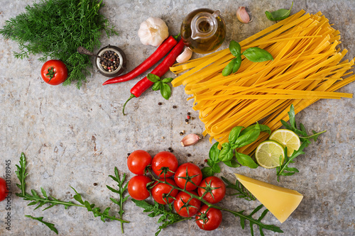 Pasta Tagliatelle and ingredients for cooking (tomatoes, garlic, basil, chili). Top view