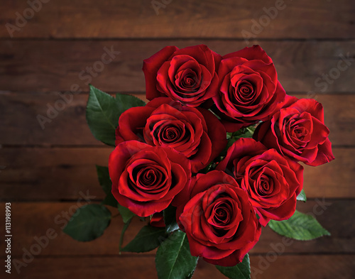 Bouquet of red roses on a dark wooden background. Top view