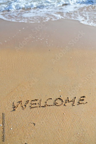 Background with welcome word sign on sandy beach outside texture