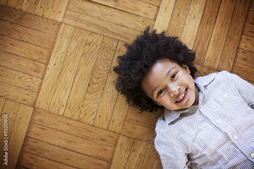 Portrait of happy boy lying on wooden floor photo