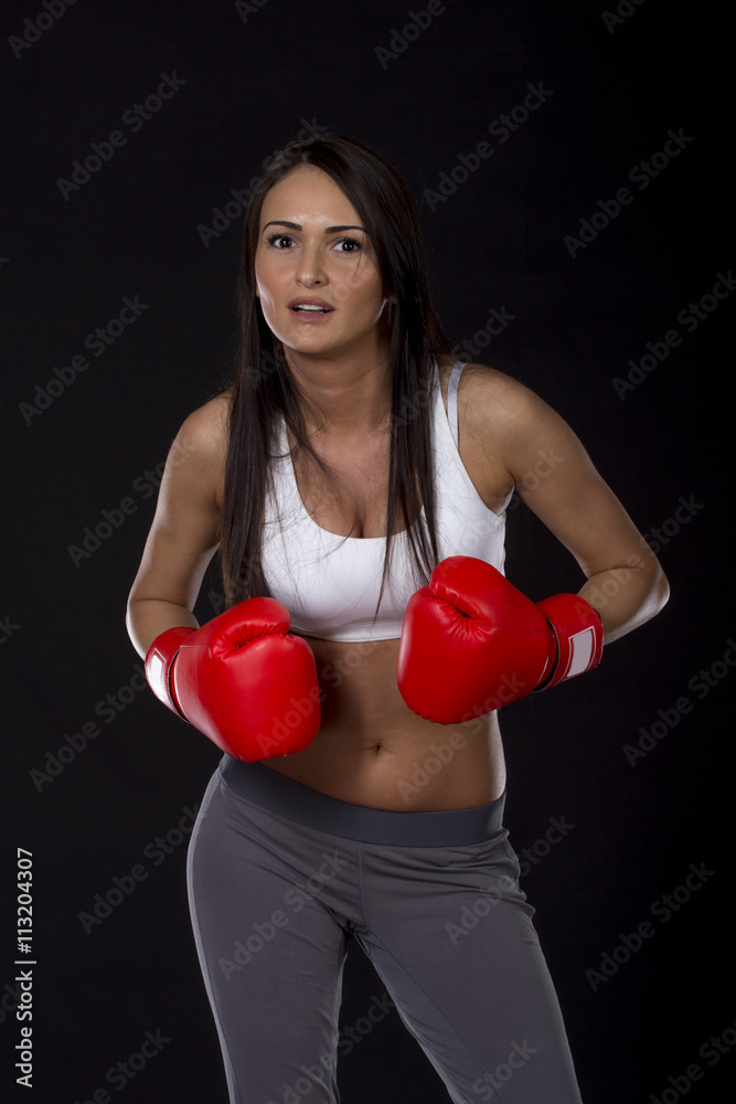 Long dark hair beautiful girl with red boxing gloves on her hands and fitness dress ready for exercise Long dark hair beautiful girl with red boxing gloves on her hands and fitness dress ready for exercise