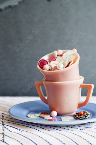 Buttons in cups stack on table against wall