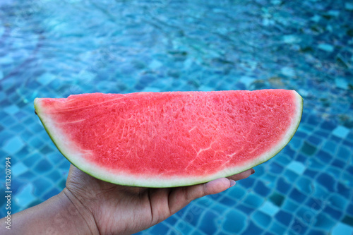 Selfie of hand with watermelon at pool