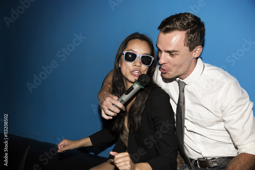 Happy couple singing karaoke in nightclub photo