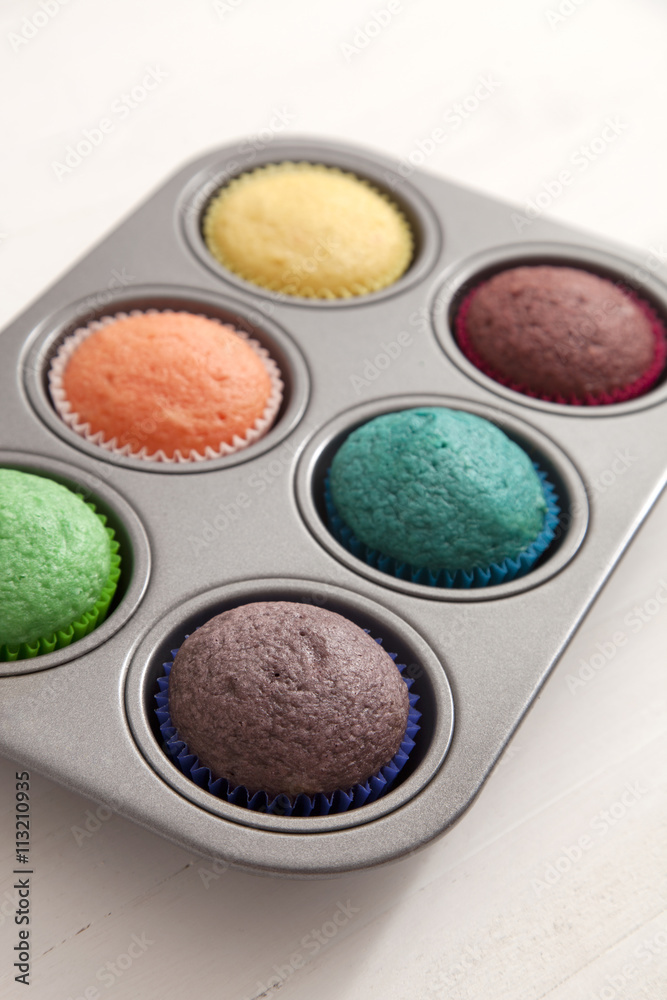 Multi colored cupcakes in tray on white background Multi colored cupcakes in tray on white background
