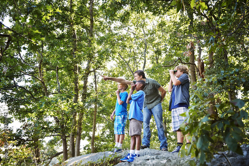 Teacher explaining students while standing on rocks in forest during field trip
