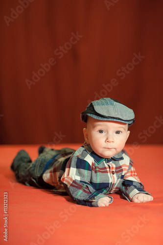 baby in tweed flat cap with a red background