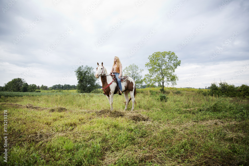 Woman looking away while sitting on horse against sky Woman looking away while sitting on horse against sky