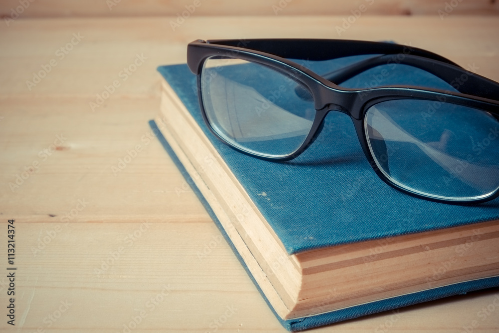 Old books and glasses on a wooden table with filter effect retro Old books and glasses on a wooden table with filter effect retro