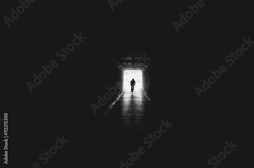 Silhouette man cycling in tunnel photo