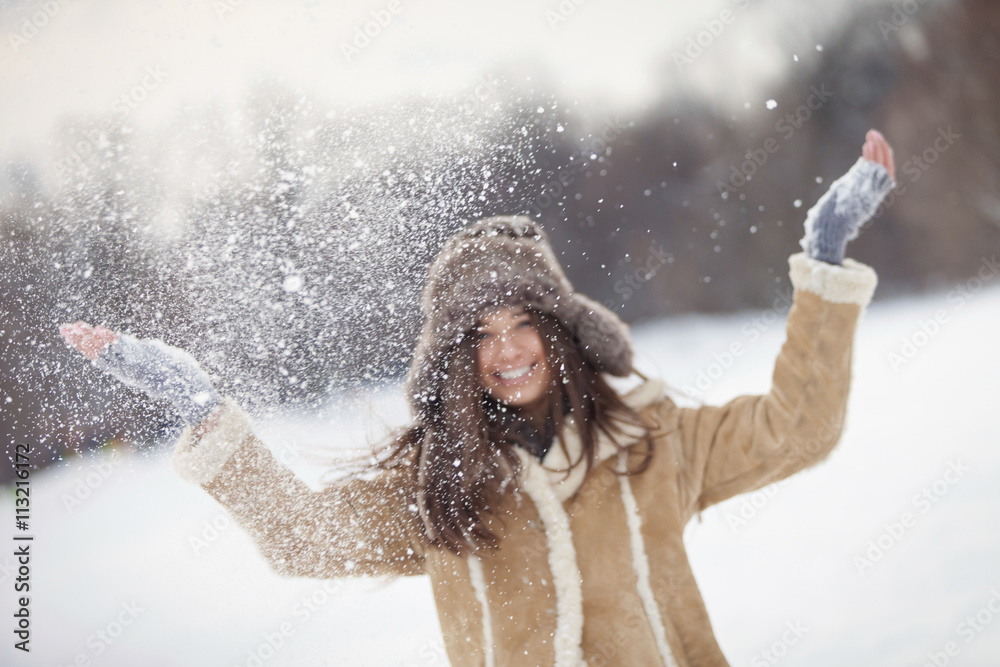 Young woman throwing snow in the air Young woman throwing snow in the air