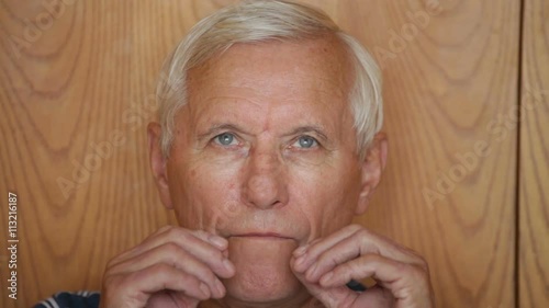 Senior man taking out denture and showing his teeth.
