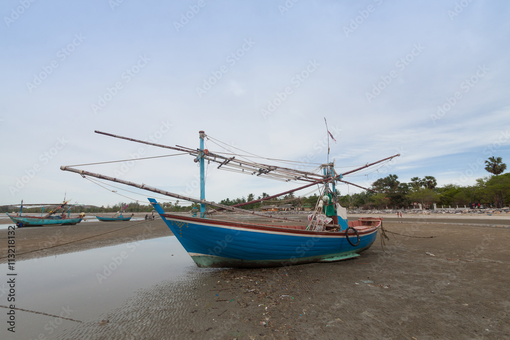 Wooden fishing boat on the  low tide beach.