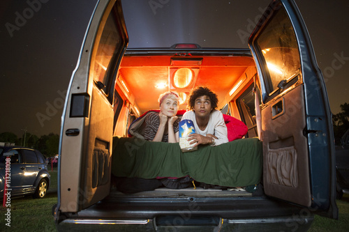 Couple watching drive-in movie from the back of van