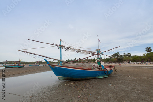 Wooden fishing boat on the  low tide beach.