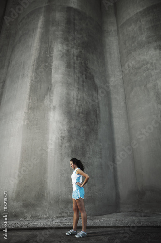 Young woman exercising against gray wall photo