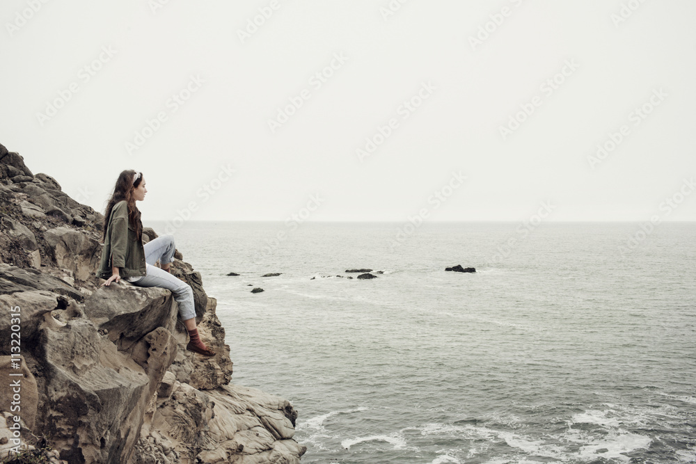 Young woman sitting on rock against sea Young woman sitting on rock against sea