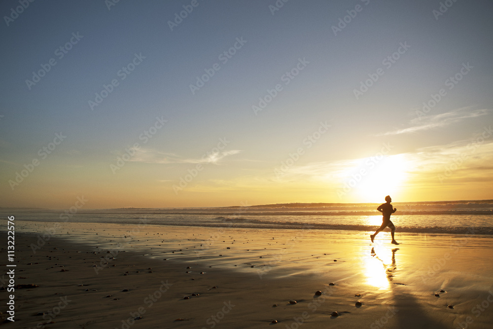 Silhouette of young man running along beach at sunset Silhouette of young man running along beach at sunset