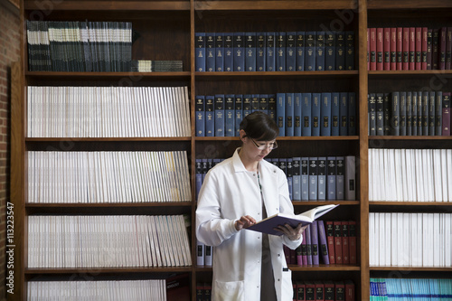 Female scientist reading book in library photo