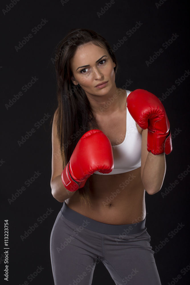 Long dark hair girl on kick box training with red gloves on her hands Long dark hair girl on kick box training with red gloves on her hands