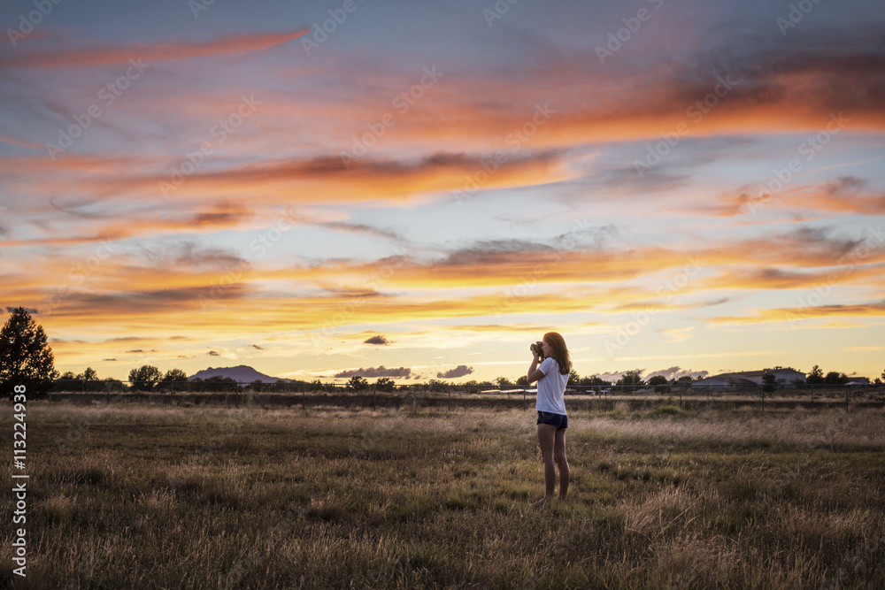 Woman taking picture with camera during sunset Woman taking picture with camera during sunset