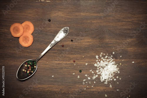 Vászonkép Salt, pepper, melchior spoon and vegetables on old wood backgrou