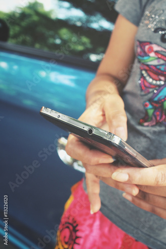 Woman using smart phone with car