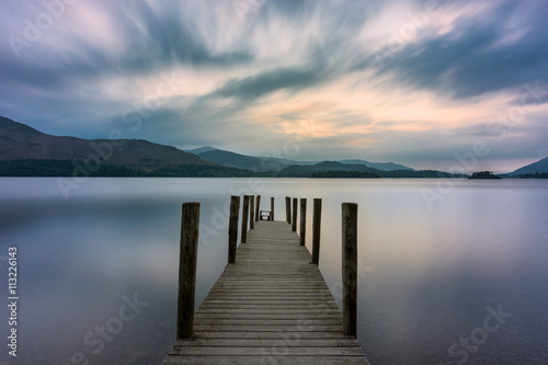 Wooden jetty leading out into lake with dramatic clouds in sky. Ashness, Derwentwater, Keswick, Lake District, UK. photo