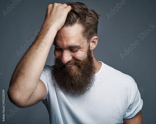 Laughing bearded man holding hair and laughing