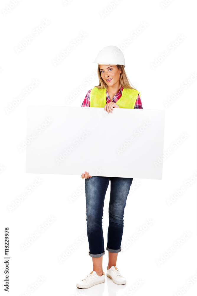 Young smiling female builder holding empty banner Young smiling female builder holding empty banner